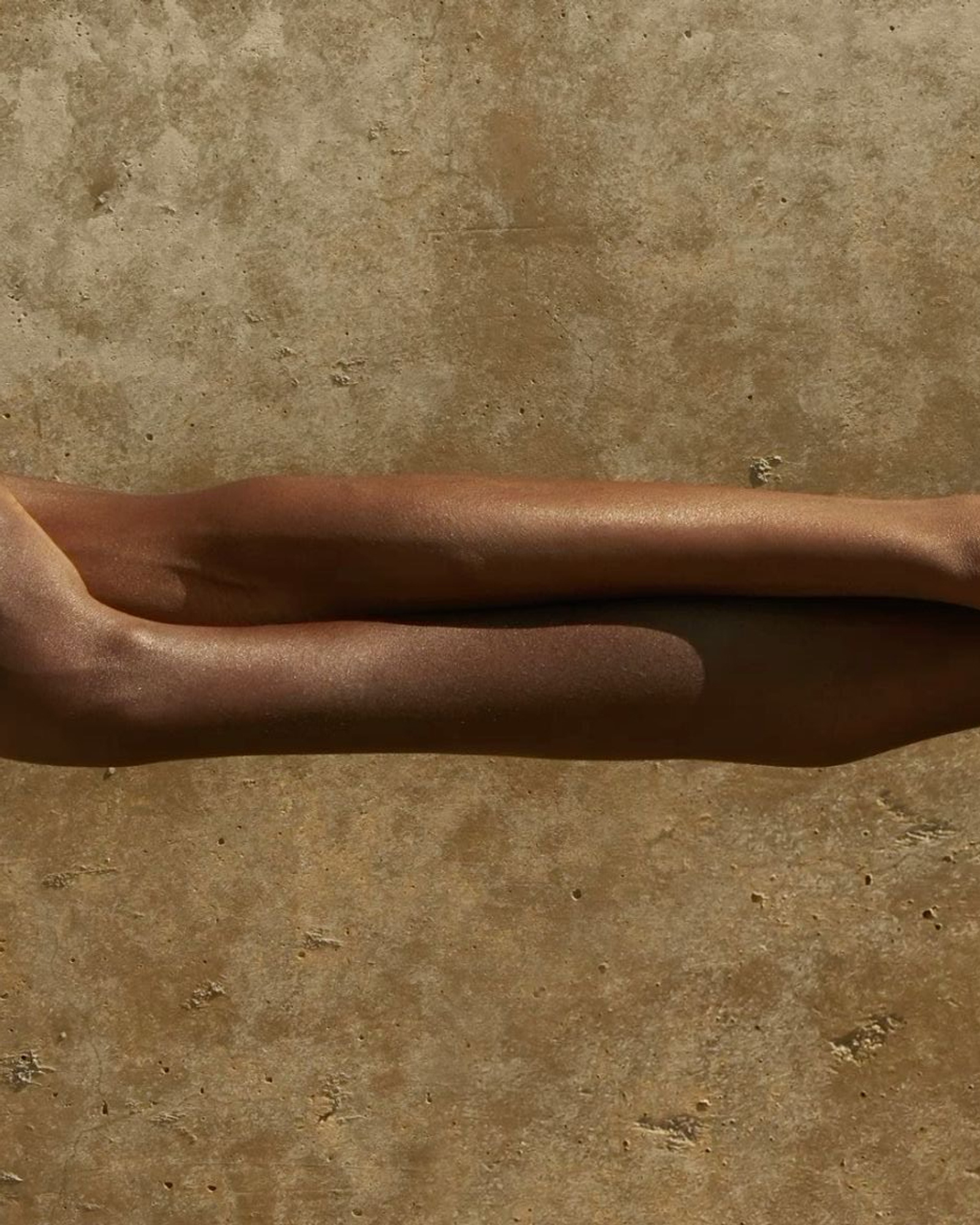 Two arms intertwined against stone